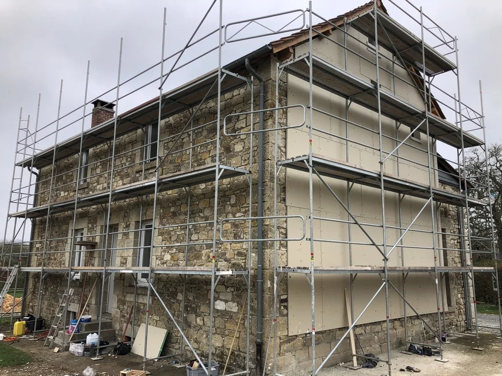 Échafaudage sur une maison en pierre pendant les travaux d'isolation extérieure
